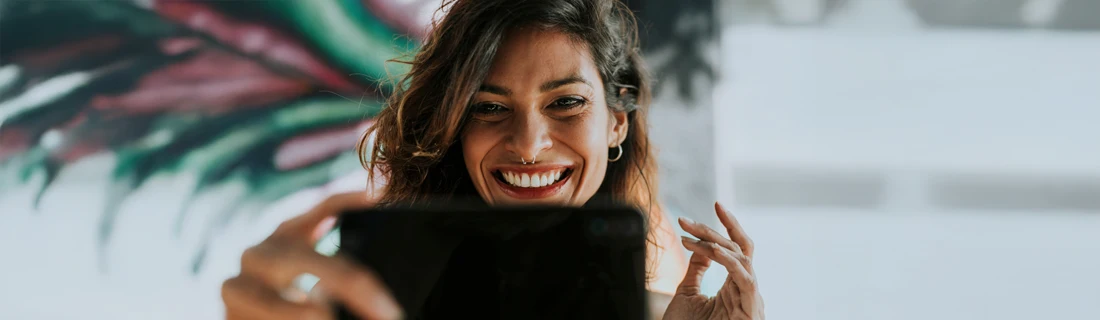 A woman smiling while looking at her phone.
